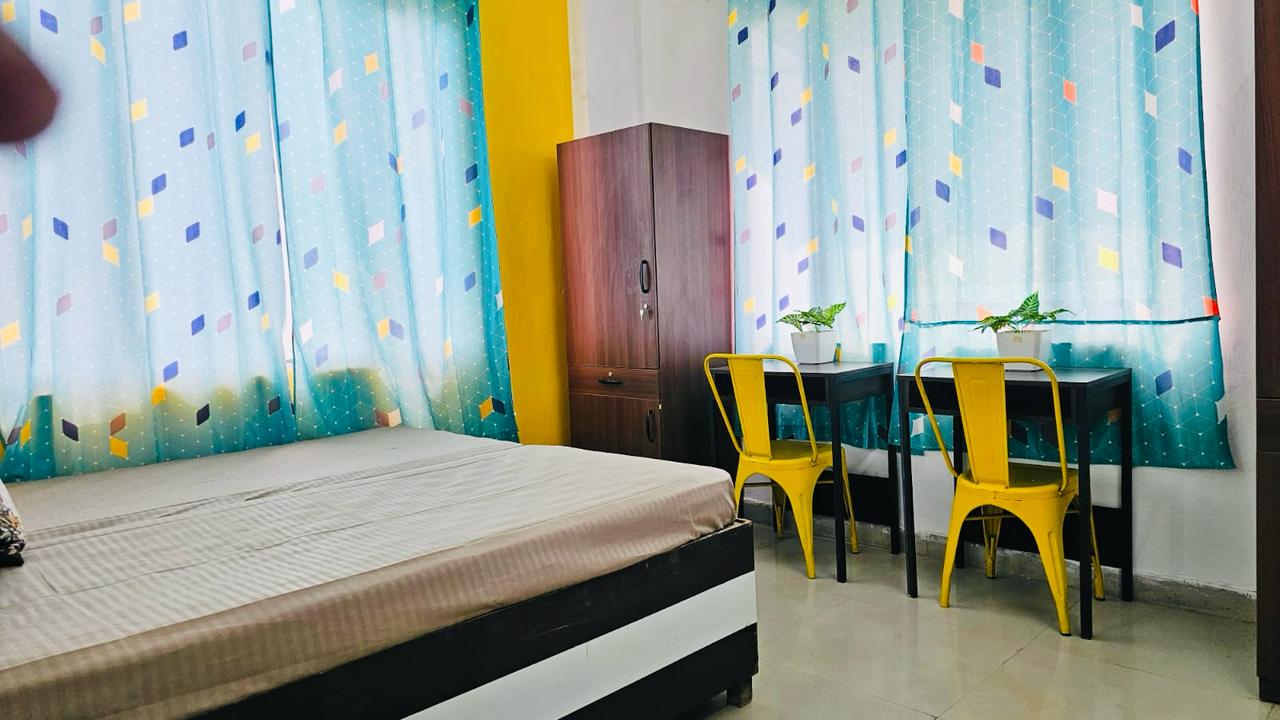 Room with bed, wardrobe, and study seating at Stag House Hostels