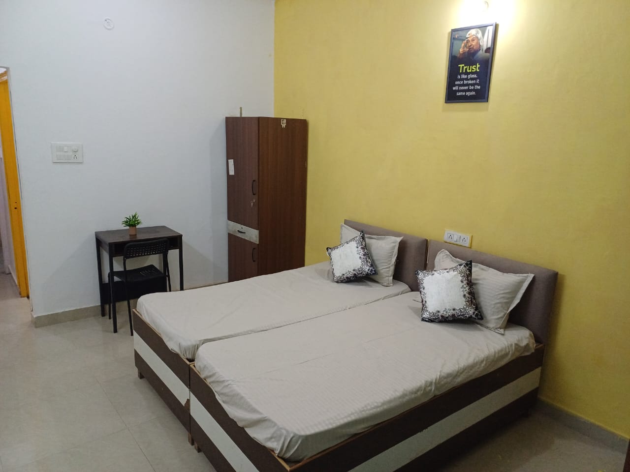 Clean student room with bed, wardrobe, and study table at Stag House Hostels